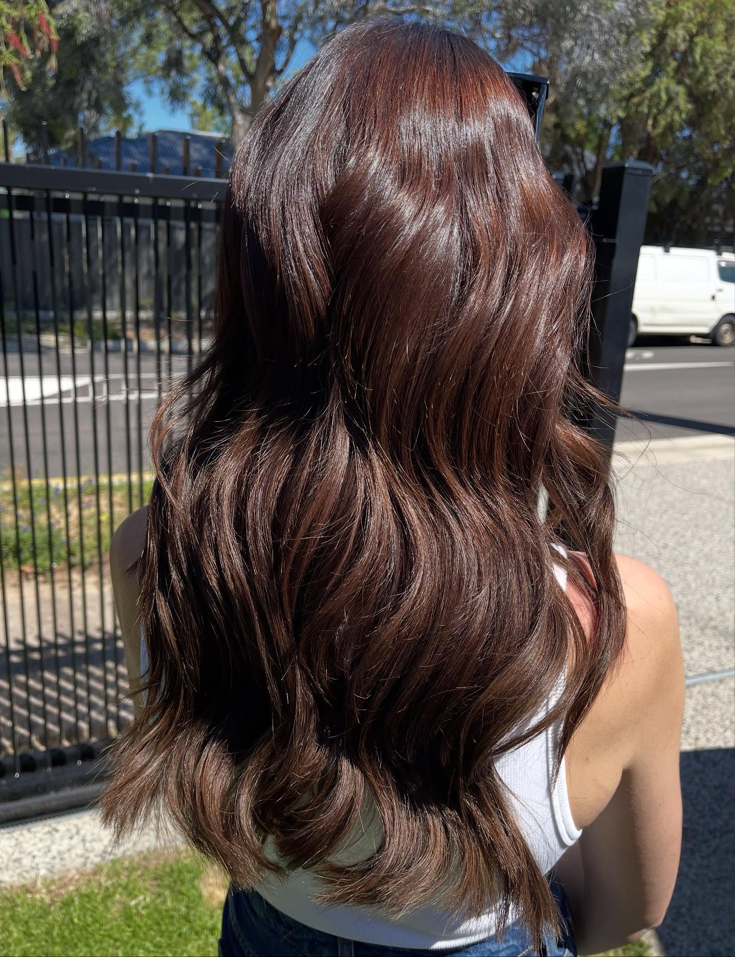 Long glossy deep auburn brown hair extensions in natural light, styled by Platinum Hair Extensions in Adelaide.
